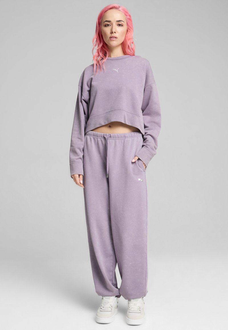 Sudadera corta morada con mangas largas y conjunto de pantalones de chándal. Tejido suave con cinturilla elástica y detalle de logo en el muslo izquierdo.