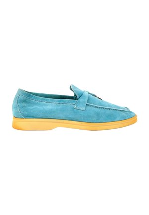 Mocassin en daim turquoise avec une semelle en caoutchouc jaune et une lanière décorative sur le dessus, vu de profil sur fond blanc.