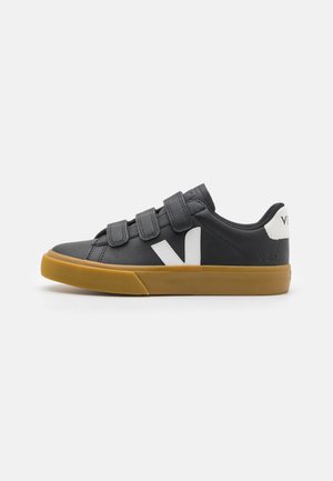 Mustad must nahkkingad Velcro rihmadega, valge külglogo ja pruuni kummitald. Ümar varvas ja madal profiil.