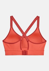 Oranžs sporta krūšturis ar teksturētu rakstu, ar krusteniskām siksnām un aizdares mehānismu. Logo uz siksnām drukāts kontrastējošā sarkanā krāsā.