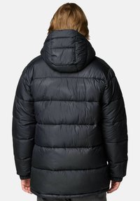 Giacca a vento nera con cappuccio, caratterizzata da sezioni trapuntate, polsini elasticizzati e una texture liscia e lucida. Vista dal retro.