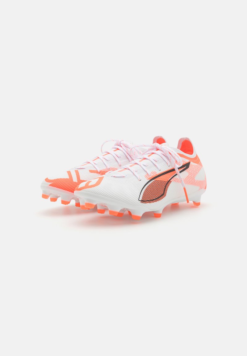 Des chaussures de foot blanches et orange avec une tige texturée, comportant un logo d'accent noir et des crampons orange proéminents pour l'adhérence.