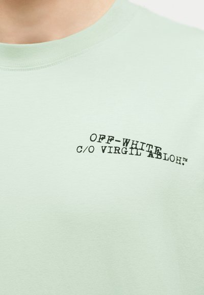 T-shirt vert clair à col rond avec texte noir "OFF-WHITE c/o VIRGIL ABLOH™" sur la partie gauche de la poitrine.