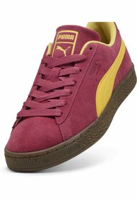 Vīna sarkanas zamšādas kedas ar dzelteniem akcentiem, ar plakanajiem šņorēm, mīkstinātu apkaklīti un teksturētu brūnu gumijas zoli. PUMA logo uz mēles.