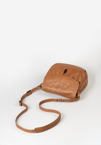 Braune Leder-Umhängetasche mit einer geschwungenen Form, ausgestattet mit einer Fronttasche, einstellbarem Riemen und subtiler Textur. Reißverschlussdetails sind sichtbar.