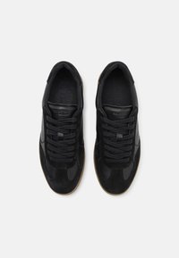 Pantofi sport negri, cu o parte superioară din suede și material sintetic, vârf rotund, șireturi texturate și o talpă din cauciuc natural.