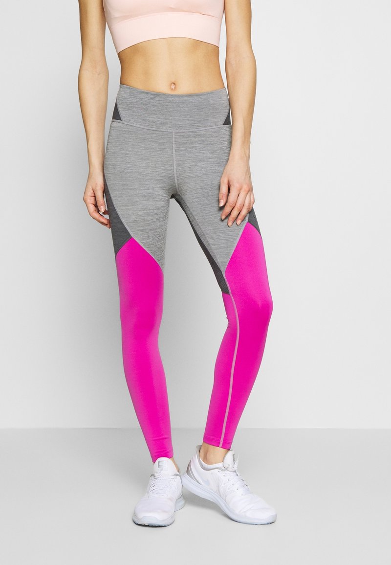 Grå och rosa leggings med en åtsittande design, som har en hög midja och geometrisk färgblockering. Matchas med vita sportskor.