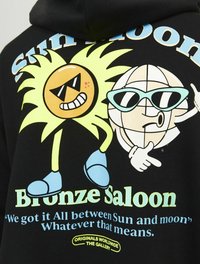 Czarna bluza z kapturem z kolorową grafiką słońca i globusa w okularach przeciwsłonecznych, z napisem "Słońce Księżyc Mosiężny Saloon" w żywych kolorach.