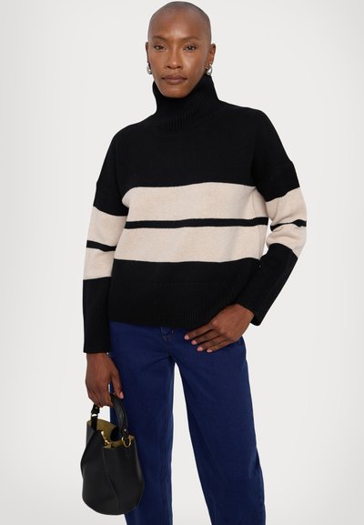 Black and beige striped knitted turtleneck sweater, featuring a relaxed fit and ribbed cuffs, paired with blue jeans and a black handbag.