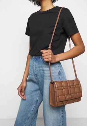 Braune gesteppten Handtasche aus Kunstleder, mit rechteckiger Form, verstellbarem Tragegurt und geprägtem Markenlogo auf der Vorderseite.