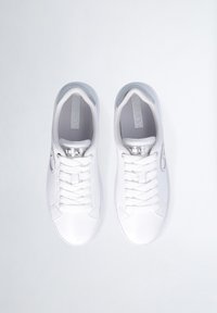 Sneaker in pelle bianca con una superficie liscia, design con lacci e sottili accenti grigi sulla linguetta e sul tallone. Dettaglio del logo in argento presente.