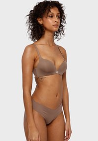 Reggiseno marrone e slip coordinati realizzati in un tessuto morbido ed elastico. Il reggiseno presenta spalline sottili e un logo discreto tra le coppe.