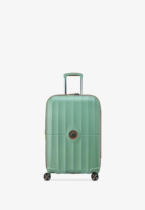 Valigia rigida di colore verde menta con scanalature verticali, dettagli marroni, manico retrattile e quattro ruote nere per la mobilità.