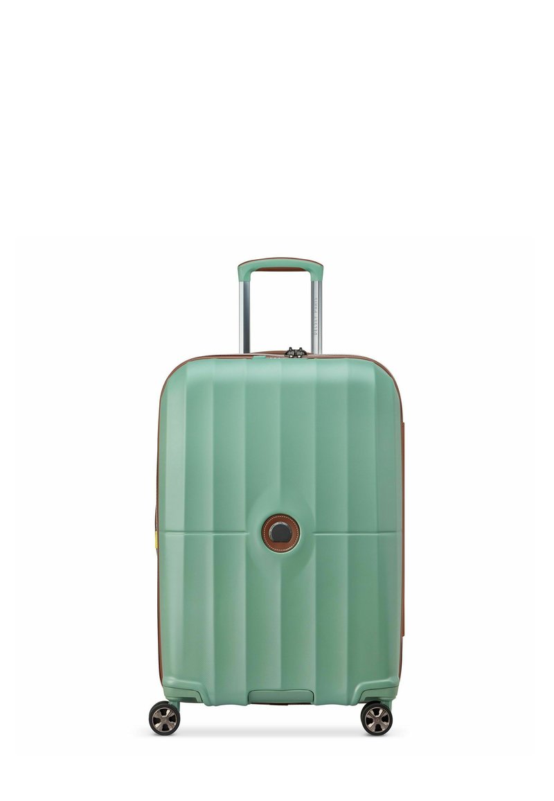 Valise rigide vert menthe avec des rainures verticales, accents marron, poignée rétractable et quatre roues noires pour la mobilité.