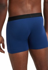 Navy blue boxer shorts with a solid black elastic waistband, featuring a smooth texture and fitted design. Visible stitching along seams.