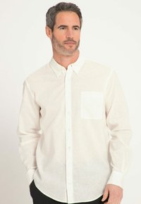 Weißes Leinen-Hemd mit Knöpfen, einer einzelnen Brusttasche, langen Ärmeln und abgerundetem Saum; bietet eine weiche, leichte Textur.