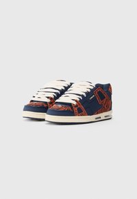 Pair of low-top sneakers with navy blue and orange tiger stripe pattern, white laces, and cream-colored soles, shown against a plain background.