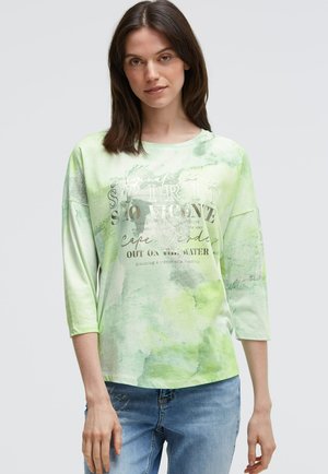 Light green long-sleeve top featuring a water-colored pattern and printed text. Soft fabric with a relaxed fit and round neckline.