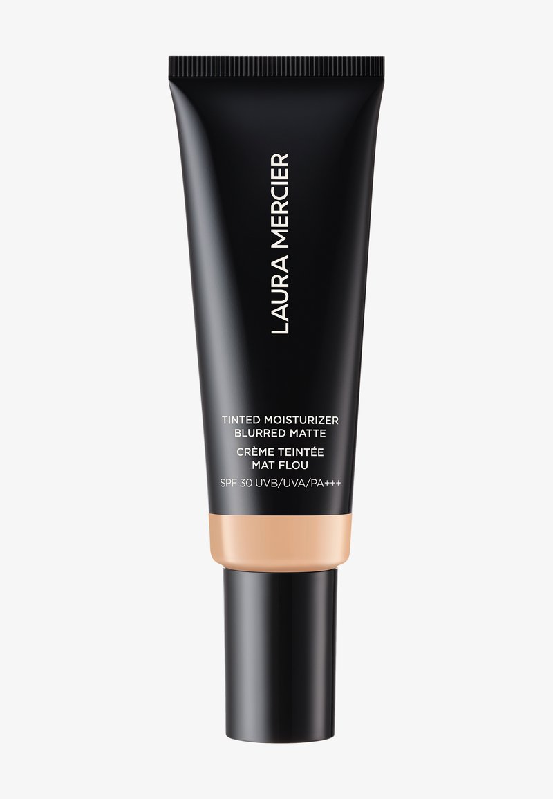 Musta putki, jossa on matta pinta ja persikkapohja. Siinä on valkoiset tekstit, joissa lukee "Laura Mercier Tinted Moisturizer Blurred Matte," SPF 30.
