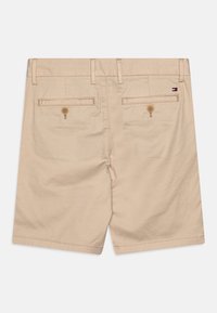 Pantaloni corti beige in cotone con una texture liscia, dotati di due tasche posteriori con chiusura a bottone e un piccolo logo sulla vita.