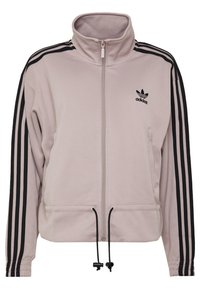 Ljusrosa zip-up jacka i mjukt tyg. Har hög krage, svarta ränder på ärmarna och justerbara snoddar i nederkant.