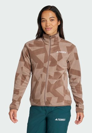 Veste en polaire marron clair avec un motif géométrique. Dotée d'un col montant, d'une fermeture zippée et d'un logo sur la poitrine gauche.