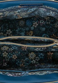 Floral-patterned interior zipper pocket in dark navy blue fabric. Textured, light blue exterior. Gold zipper detailing enhances functionality.