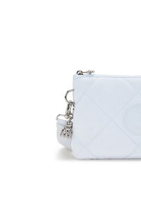 Borsa trapuntata azzurro chiaro con una texture liscia, caratterizzata da hardware argentato e un piccolo ciondolo pendente. Chiusura con zip e tracolla regolabile.