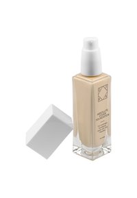 Glasflaska med beige flytande foundation och ett vitt pumplock. Etiketten har varumärkesnamn och produktinformation i svart text.
