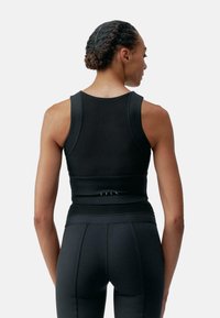 Must have mustal sportlik lühikesed top, mis on valmistatud siledast venivast kangast. Omab laia rihmaid, istuvat siluetti ja tagasi peeneid õmblusi.