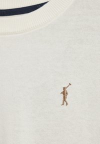 Krämfärgad stickad tröja med ribbat rundhals. En liten, broderad brun logotyp av en golfare är placerad på vänster bröstparti.