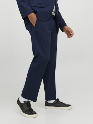 Marina kostymbyxor med skräddarsydd passform, mjuk textur och sidofickor; matchat med svarta sneakers och vita ankelsockor.