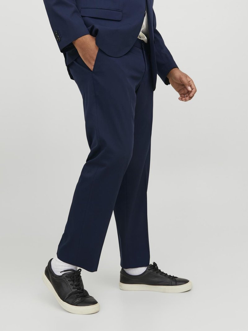 Pantaloni de costum bleumarin cu o croială ajustată, textură moale și buzunare laterale; asortați cu adidași negri și șosete albe până la glezne.