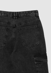 Pantaloni in denim neri con vita alta, tasche a toppa e dettagli di cucitura sottili. La texture è liscia con una leggera elasticità.