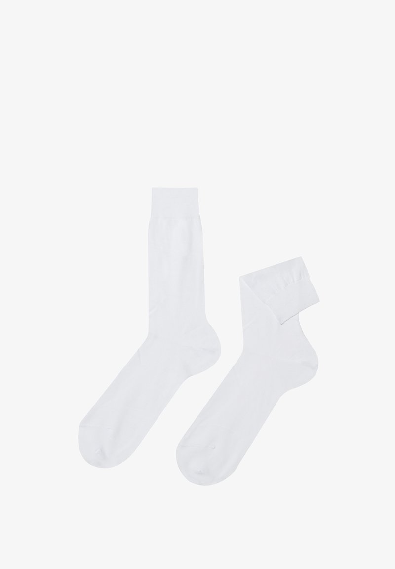 Calzini di cotone bianchi con una texture liscia, caratterizzati da un design a lunghezza media e un bordo a coste. Un calzino è arrotolato.