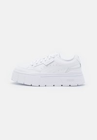 White leather platform sneakers with a textured upper, featuring a rounded toe, lace-up design, and prominent rubber sole with angular accents.
