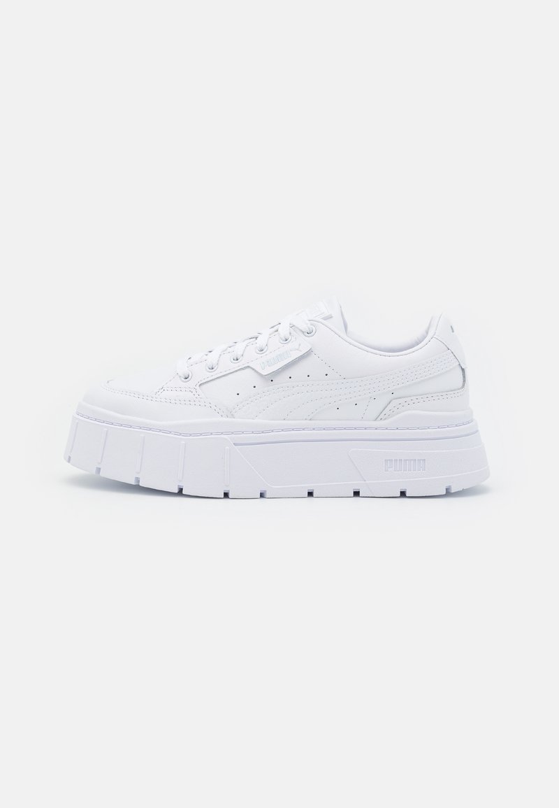 White leather platform sneakers with a textured upper, featuring a rounded toe, lace-up design, and prominent rubber sole with angular accents.