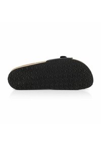 Semelle extérieure en caoutchouc noir avec un motif en vagues texturé ; intercalaire beige ; tige noire lisse avec un accent circulaire près du talon.