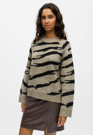 Gestrickter Pullover mit einem beige-schwarz gestreiften Muster, rundem Halsausschnitt und langen Ärmeln, kombiniert mit einem braunen Kunstlederskirt.
