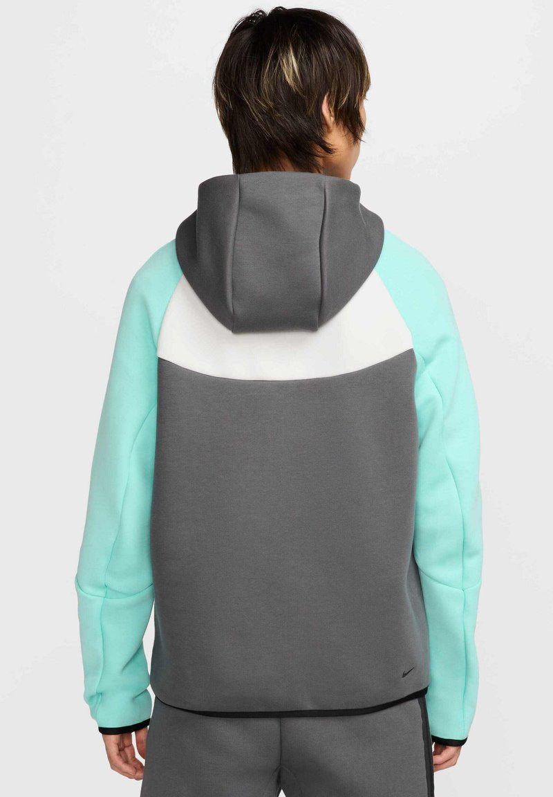 Sudadera gris y menta con un panel blanco en la parte superior de la espalda, con capucha ajustable y puños de canalé. Accesorios negros en el dobladillo.