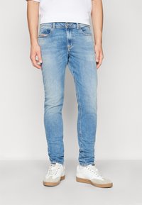 Ljusblå denimjeans med slim fit, femficksdesign och subtila blekningar. Matchas med vita sneakers med beige detaljer.