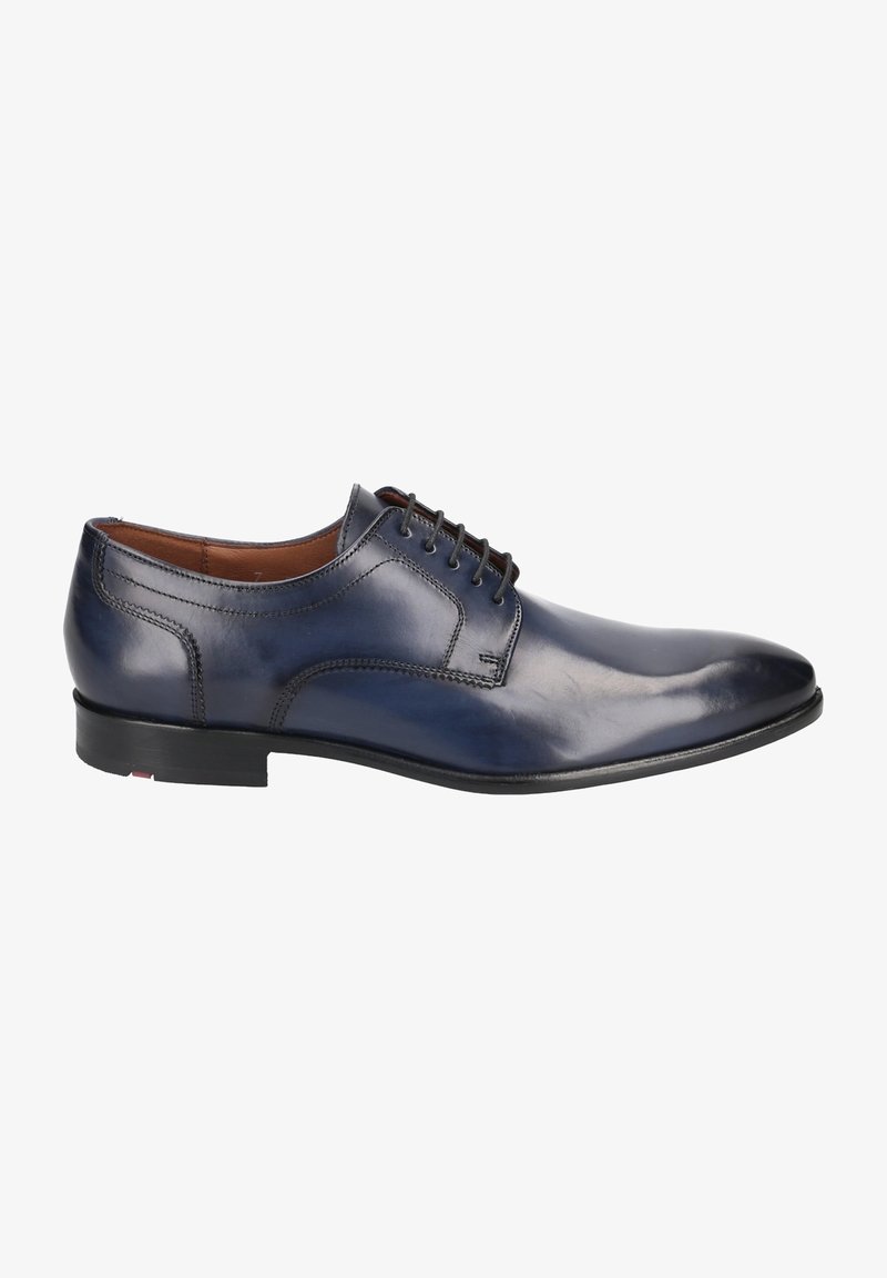 Chaussure habillée en cuir bleu marine pour homme, à lacets, avec détails cousus et petit talon noir, affichée de profil sur fond blanc.