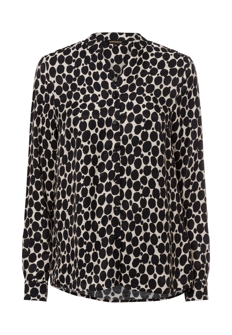 Schwarz-weißes Blusenshirt mit langen Ärmeln, das ein gepunktetes Muster, einen runden Kragen und eine einzelne Brusttasche aufweist. Glatte Stofftextur.