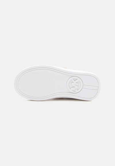 Σόλα ενός λευκού αθλητικού παπουτσιού με υφή και κυκλικό λογότυπο MK χαραγμένο κοντά στη φτέρνα πάνω σε απλό ανοιχτό φόντο.