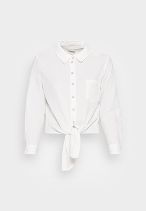 Chemise blanche à col pointu, avec un design à nouer à l'avant, manches longues et une poche poitrine unique. Texture lisse avec un motif subtil.