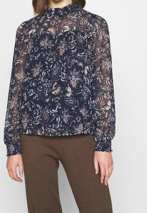 Blusa floreale navy in tessuto trasparente con maniche lunghe, scollatura arricciata e polsini arricciati; presenta motivi intricati in rosa e bianco.
