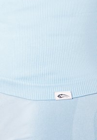 Lys blå ribbet striktrøje med en glat tekstur og et lille hvidt mærke med et sort design i kanten.