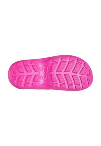Semelle en caoutchouc rose vif avec motifs de grip texturés, comprenant des éléments circulaires et rectangulaires, et un logo de marque en relief au centre.