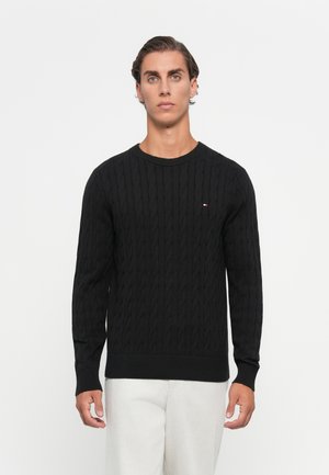 Schwarzer Strickpullover im klassischen Rundhalsausschnitt-Design; verfügt über ein strukturiertes Muster und gerippte Bündchen und Saum. Kleines Logo auf der Brust.