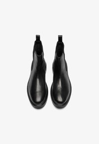 Botas de tobillo de cuero negro con un acabado suave, paneles laterales elásticos y tiradores para ponérselas fácilmente. Punta redondeada y suela de goma plana.